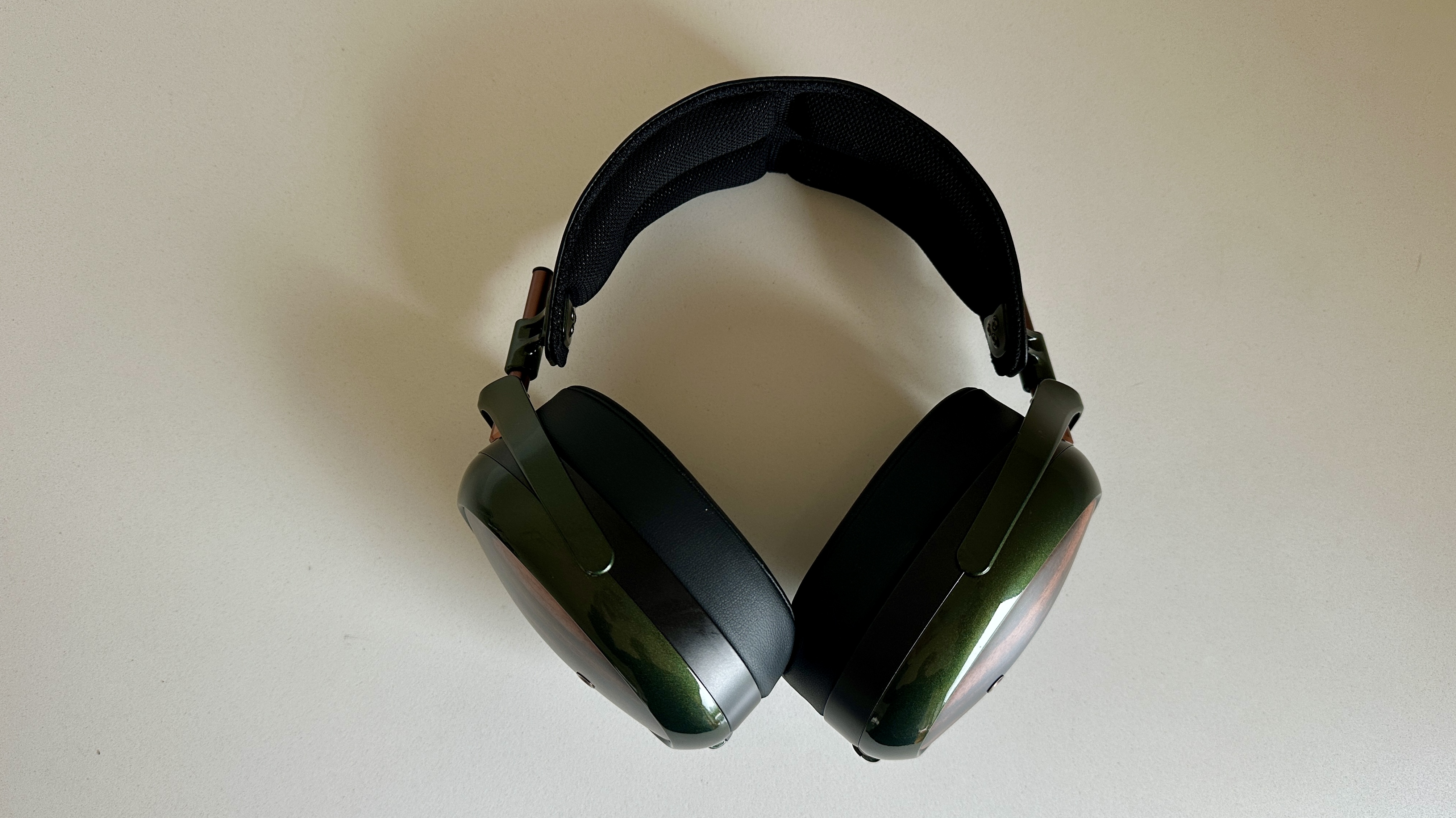 Meze Audio Strada headphones with wooden ear cups, in close-up and with their case and cables visible, on a white table