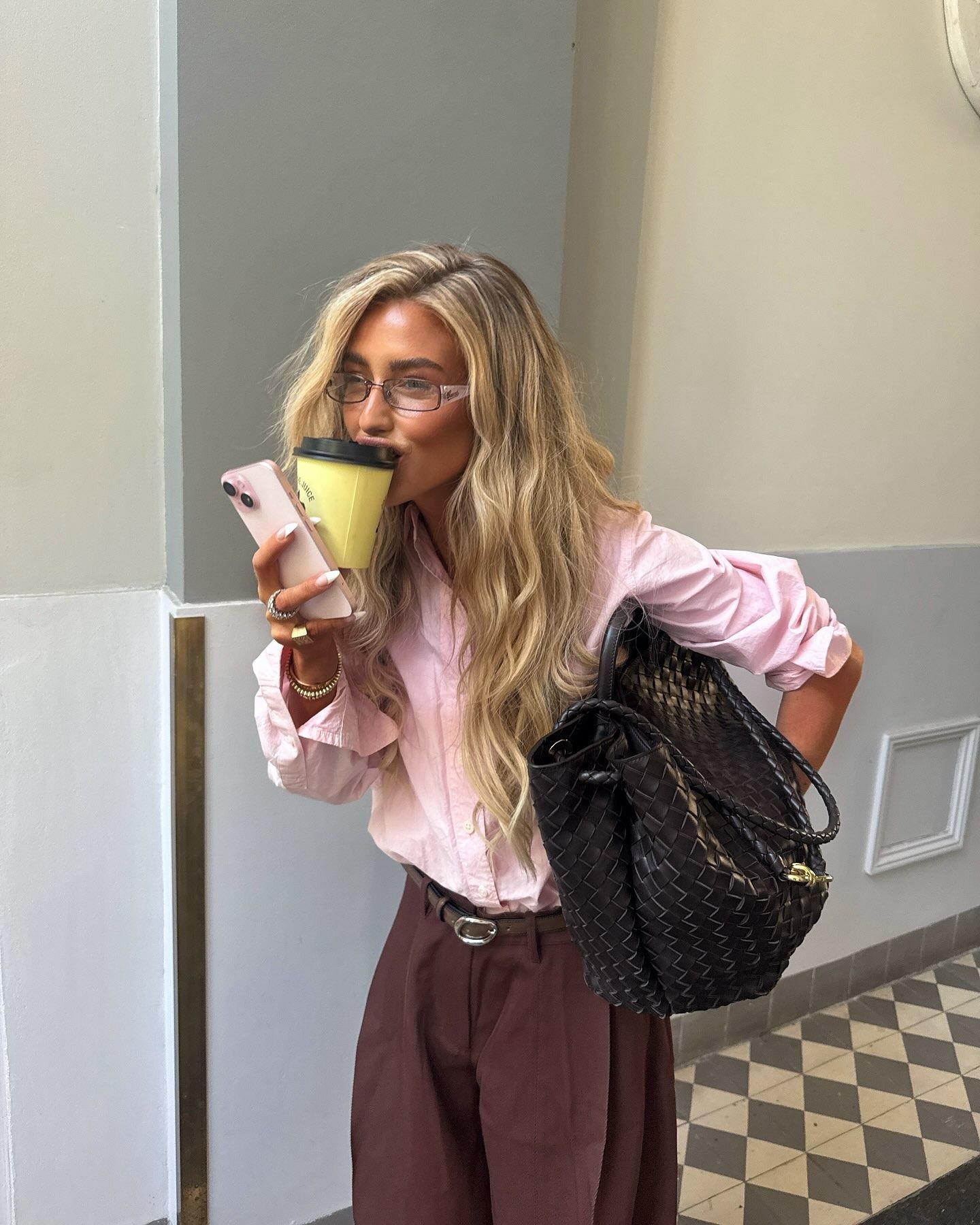 A woman drinking a coffee with creamy blonde, wavy hair
