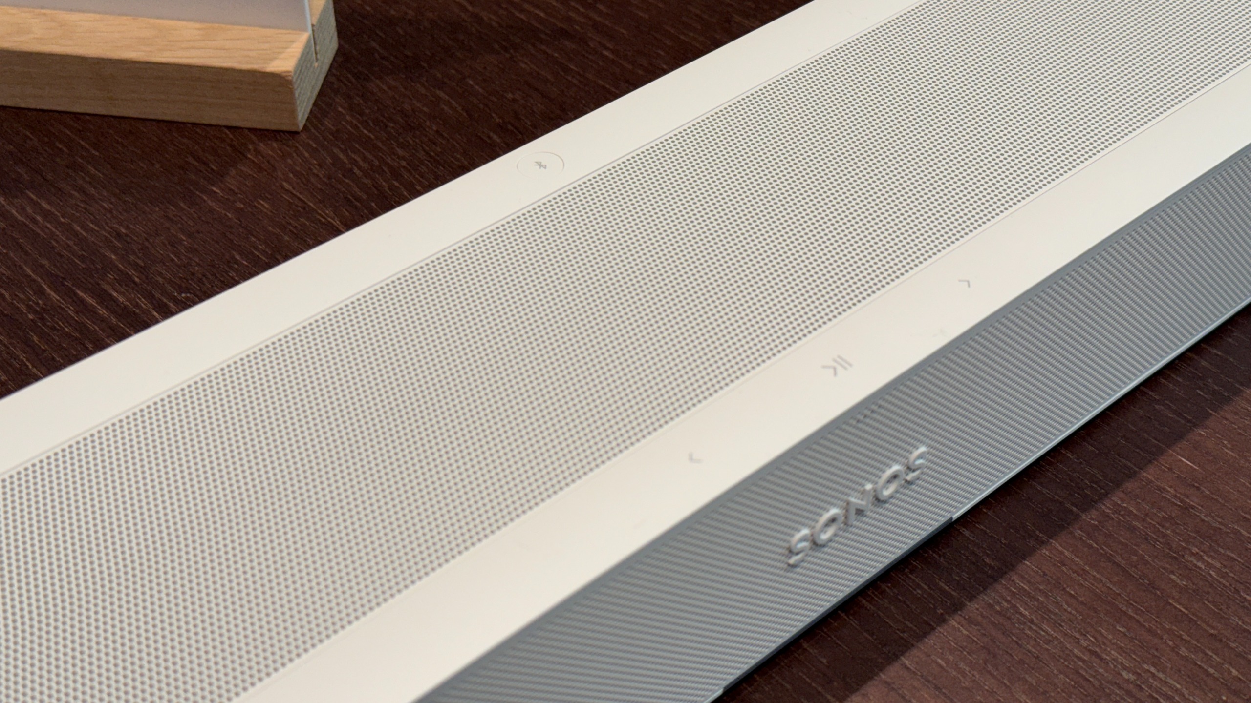 The Sonos Beam Ultra on a wooden table showing its top buttons