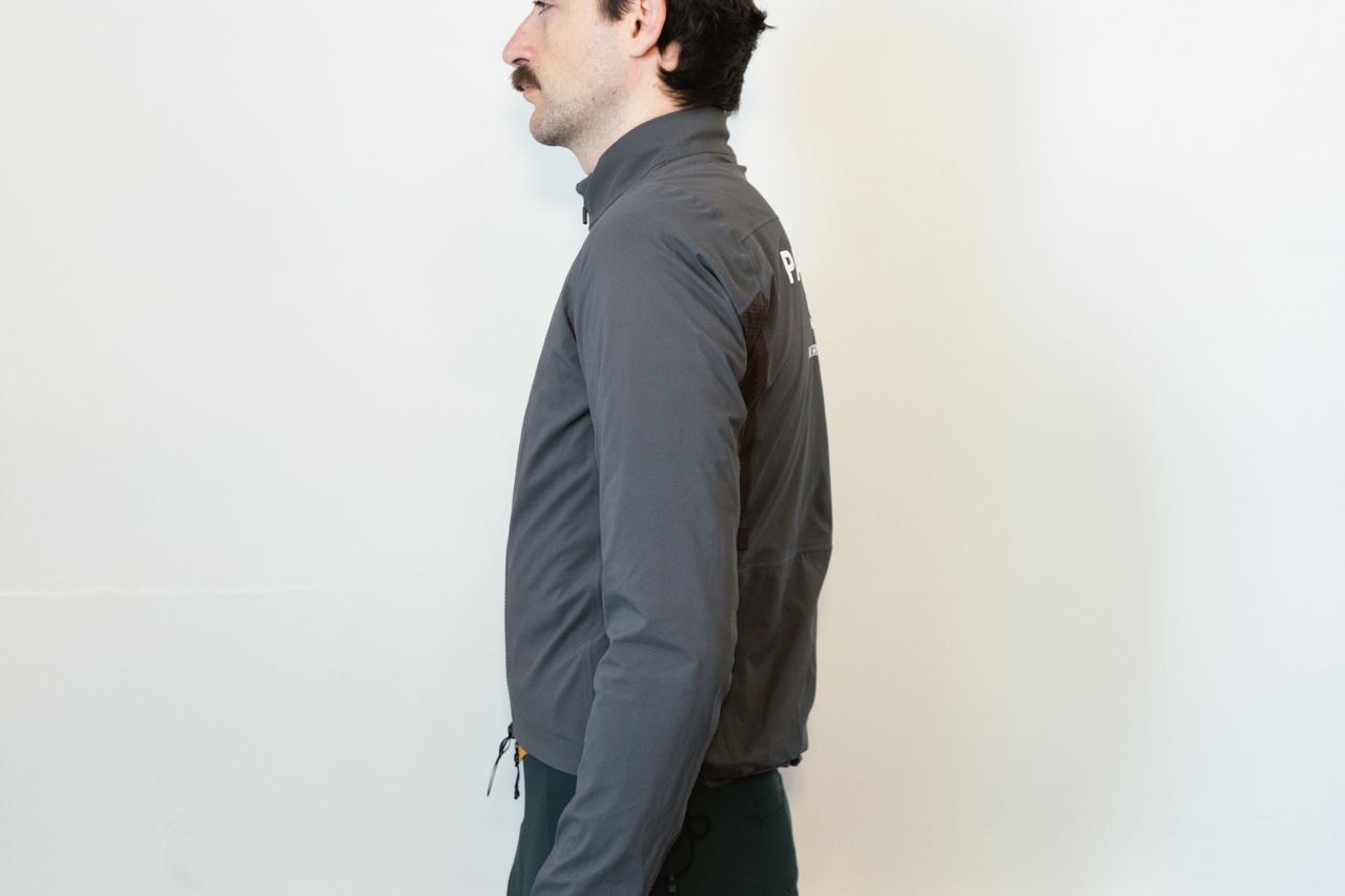 A man in a grey waterproof jacket against a white wall