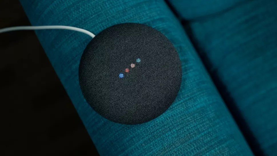 Speaker Google Nest Mini dengan latar belakang biru