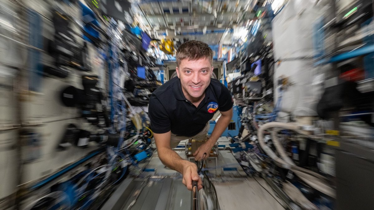 an astronaut on the space station with the background blurry behind him