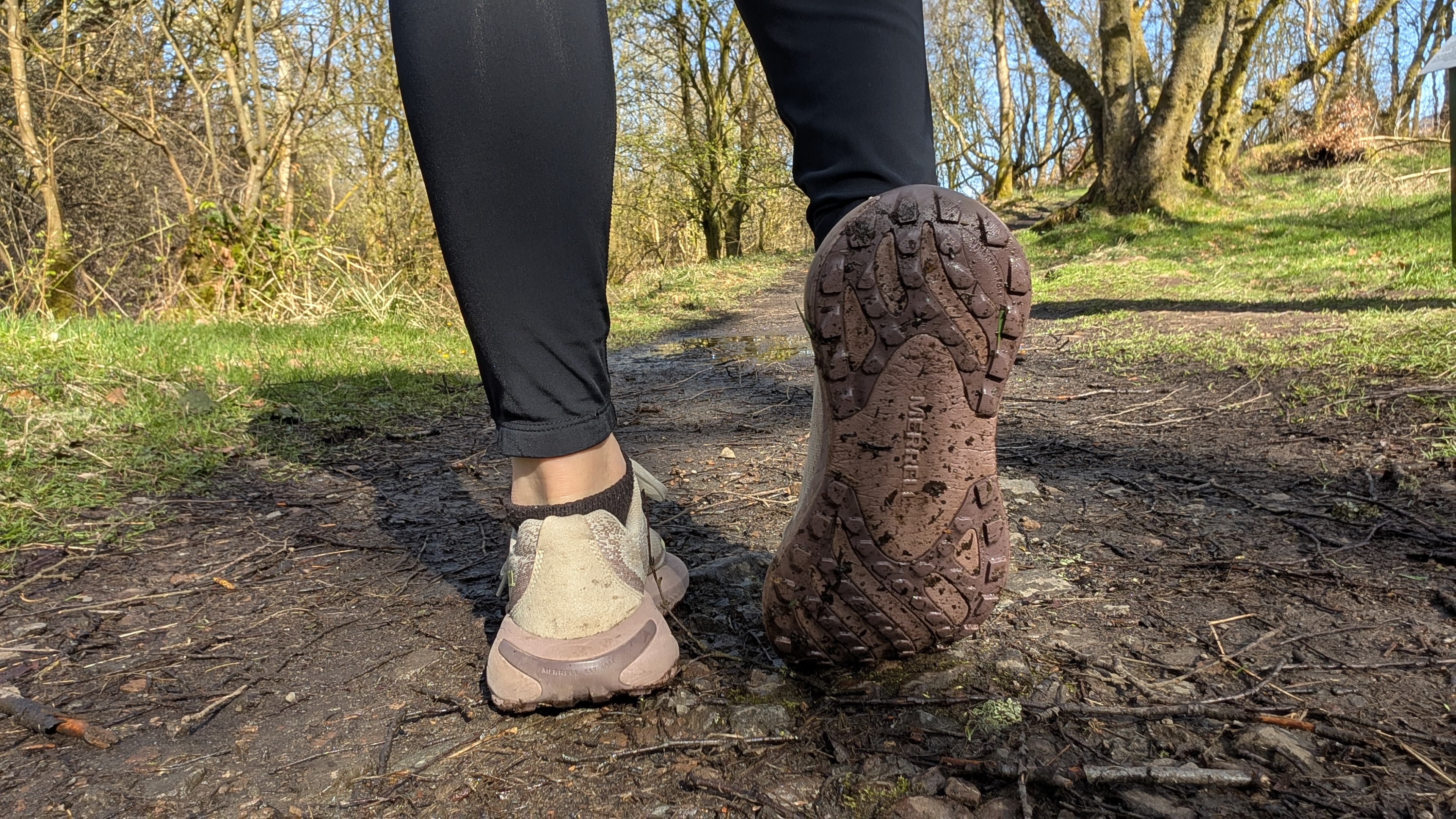 A runner's feet wearing the Merrell Morphlite trail running shoes and showing the sole of one of the shoes