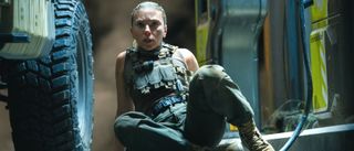 Scarlett Johansson looks forward in terror next to a gas pump in Jurassic World Rebirth. 