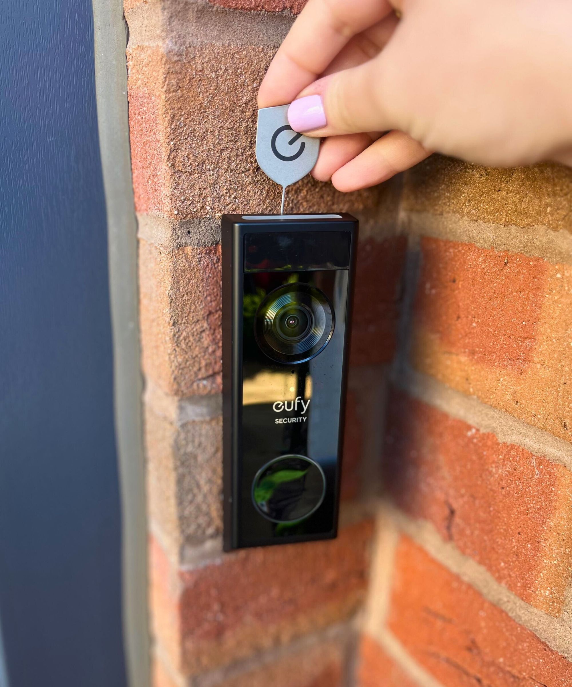 A hand pushing the metal key into the top of the eufy E340 video doorbell mount to release it