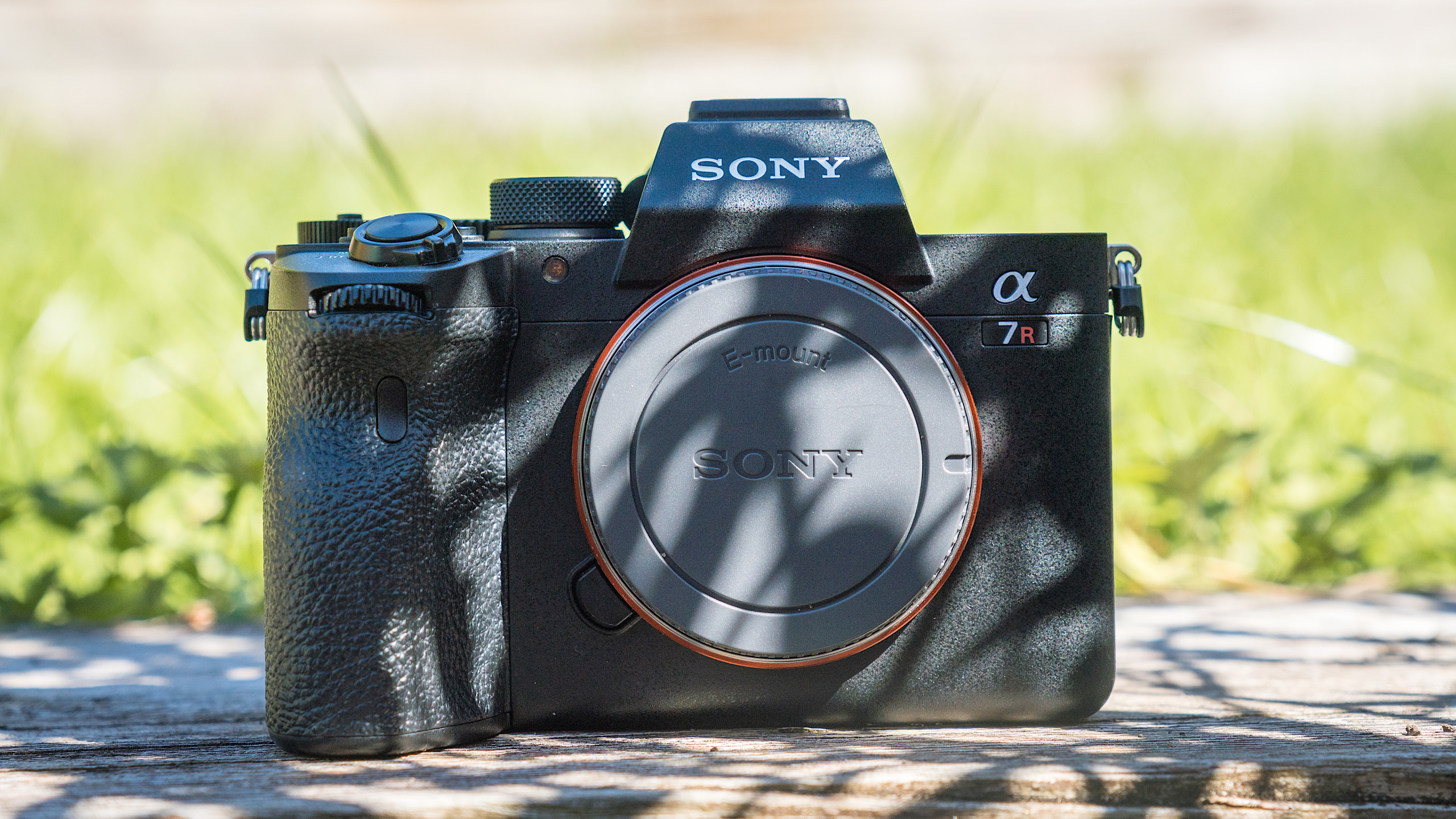 Front view of the Sony a7r iv resting on a wooden table outside