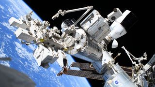 a sprawling photo of four space station modules, two robotic arms, two spacecraft and a payload porch in Earth orbit