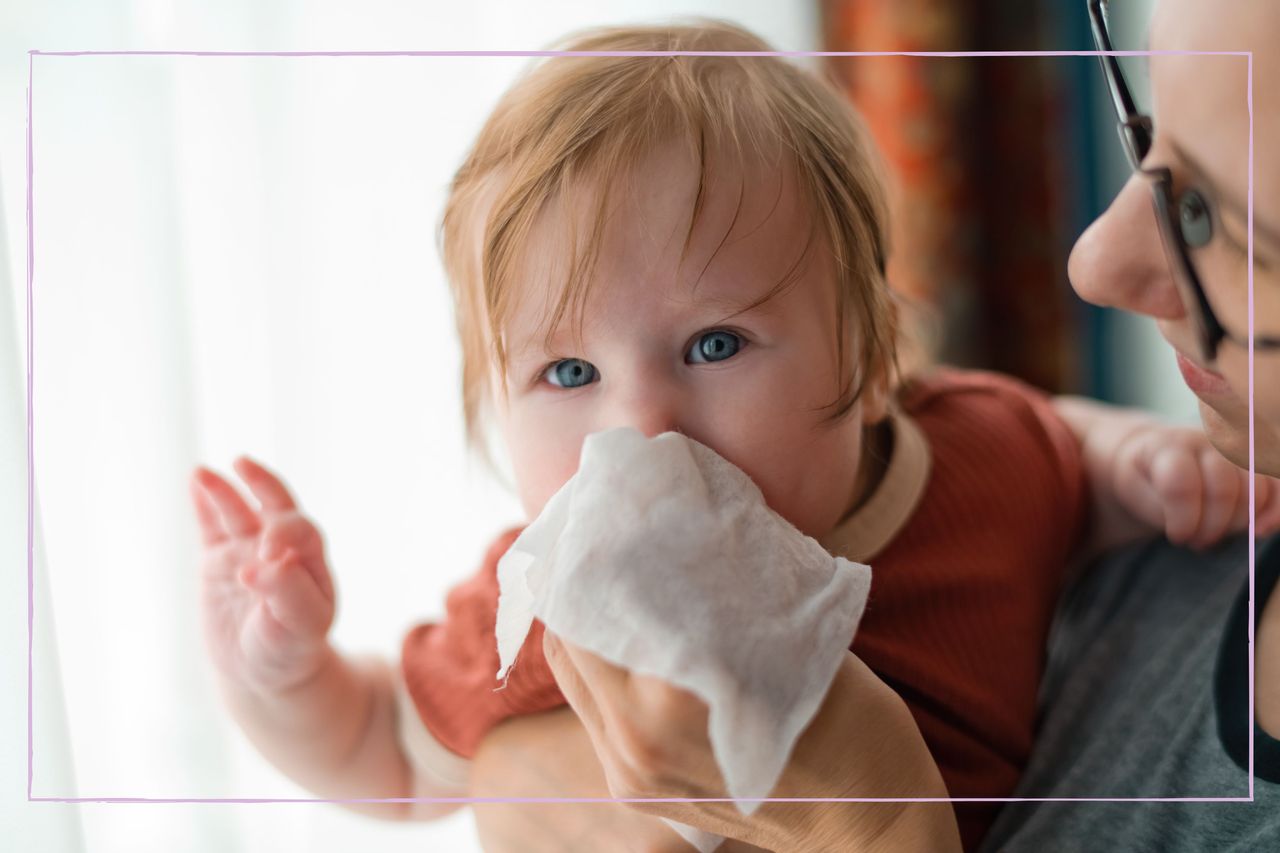 A woman holding a tissue to a baby&#039;s nose