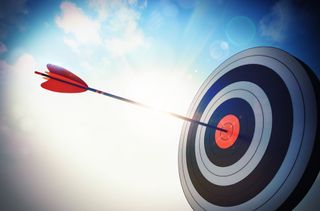 Closeup of a dartboard with a dart in the center on a sunny day