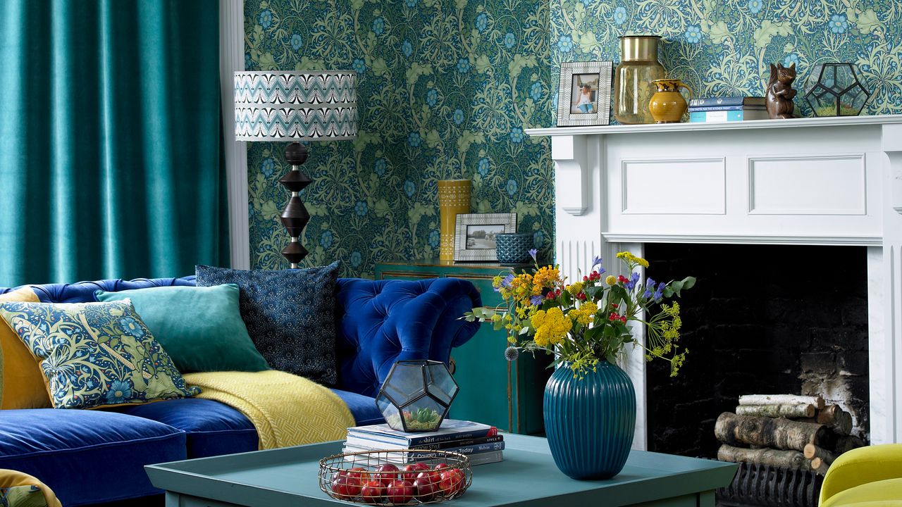 Blue living room with blue velvet sofa, heavy curtains and a white fireplace