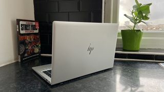 The back of the HP EliteBook 840 G7 with flower pot and cookbook in background