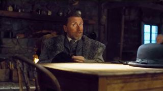 Tim Roth sitting at his table asking questions in The Hateful Eight