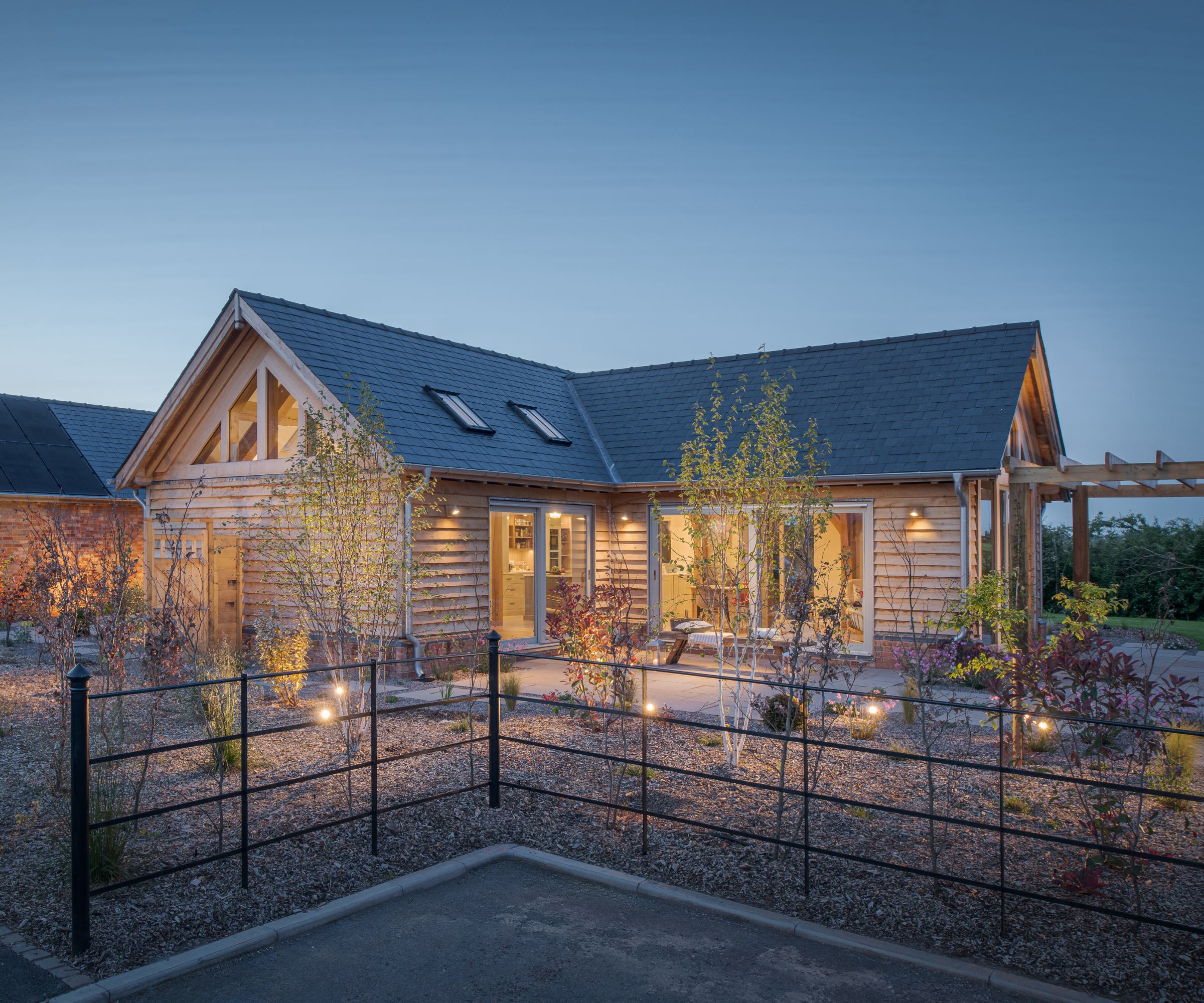 single storey timber frame home lit up at night