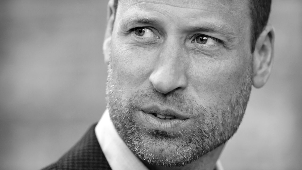 A black and white headshot of Prince William looking to the left