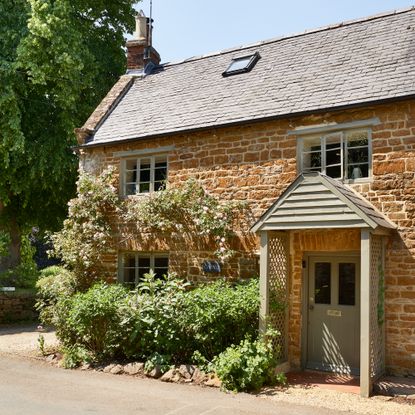 exterior of a cotswolds cottage with green painted window frames and door