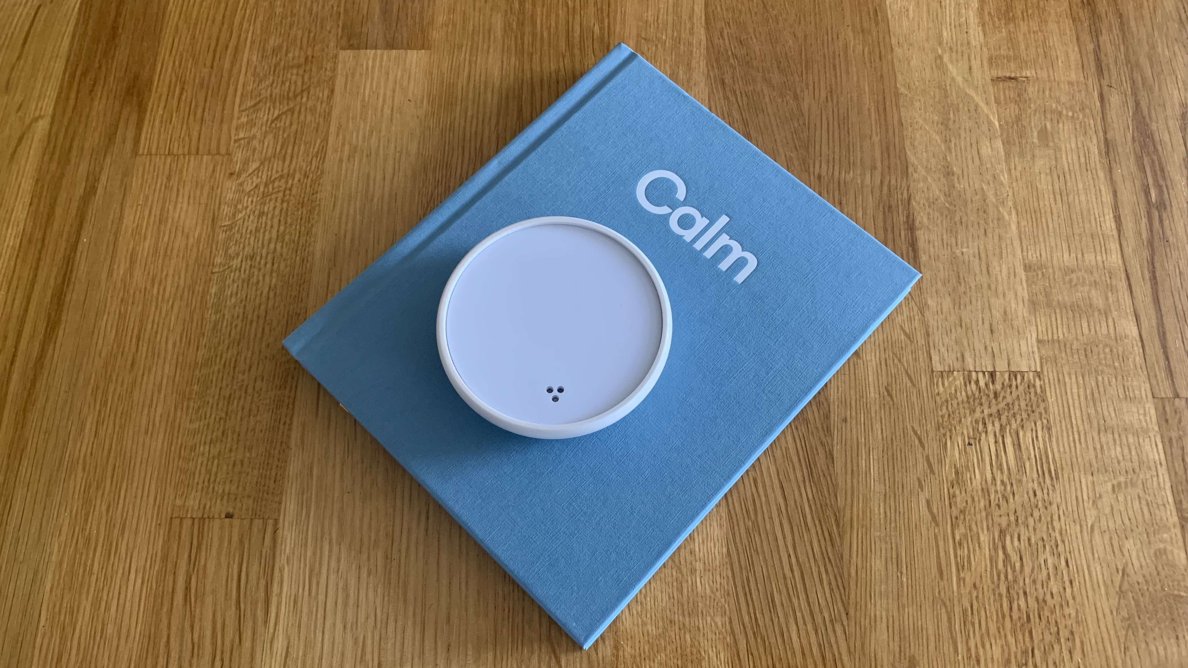 The original Dodow sleep device placed on a blue book with the word Calm at the top