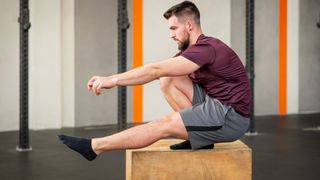 Man performing pistol squat on box at gym