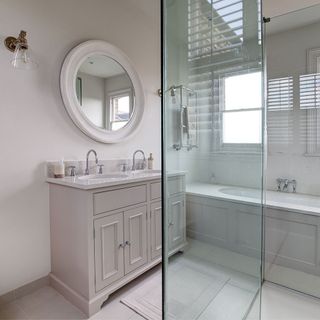 bathroom with white drawers and glass partition