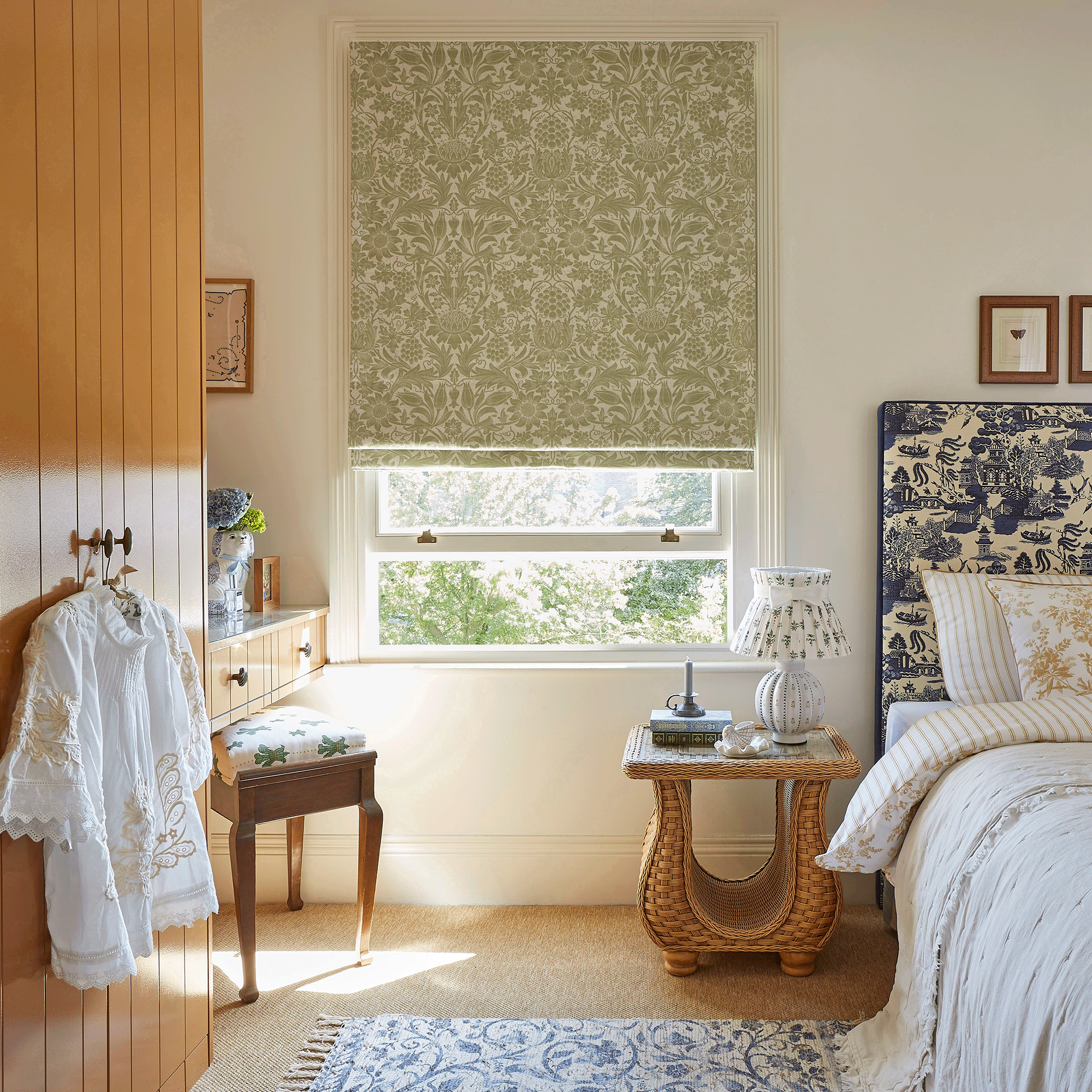William Morris green blind in a white bedroom with a blue headboard