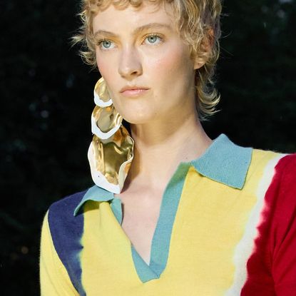 A model with a curly short wolf cut walking the runway.