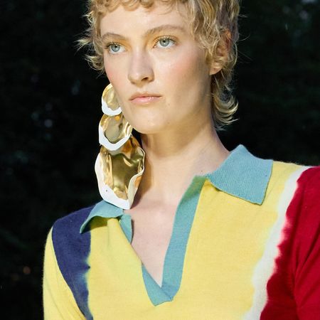 A model with a curly short wolf cut walking the runway.