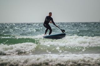 Person surfing/paddle boarding wearing wetsuit
