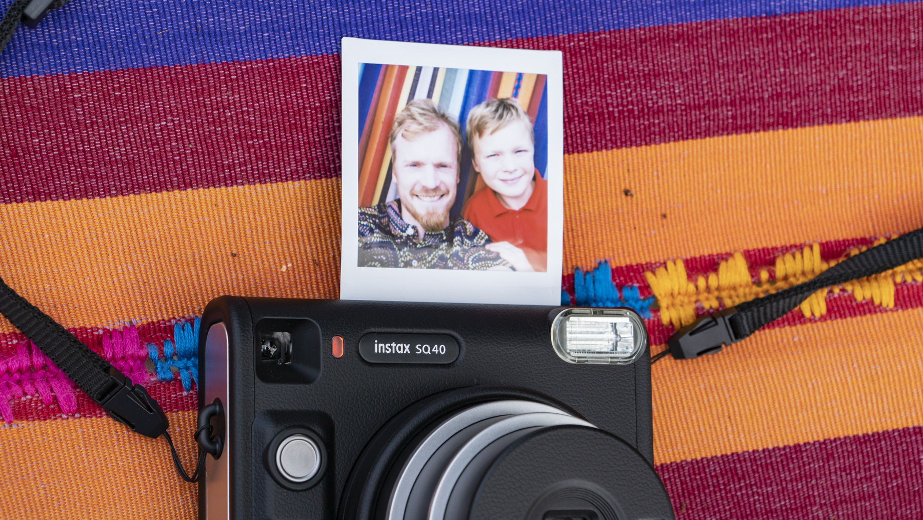 Fujifilm Instax SQ40 camera on a multi-color fabric background with print