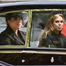 Princess Beatrice and Princess Eugenie wearing black riding in a car
