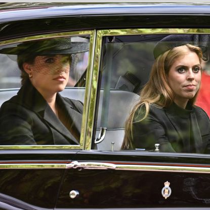 Princess Beatrice and Princess Eugenie wearing black riding in a car