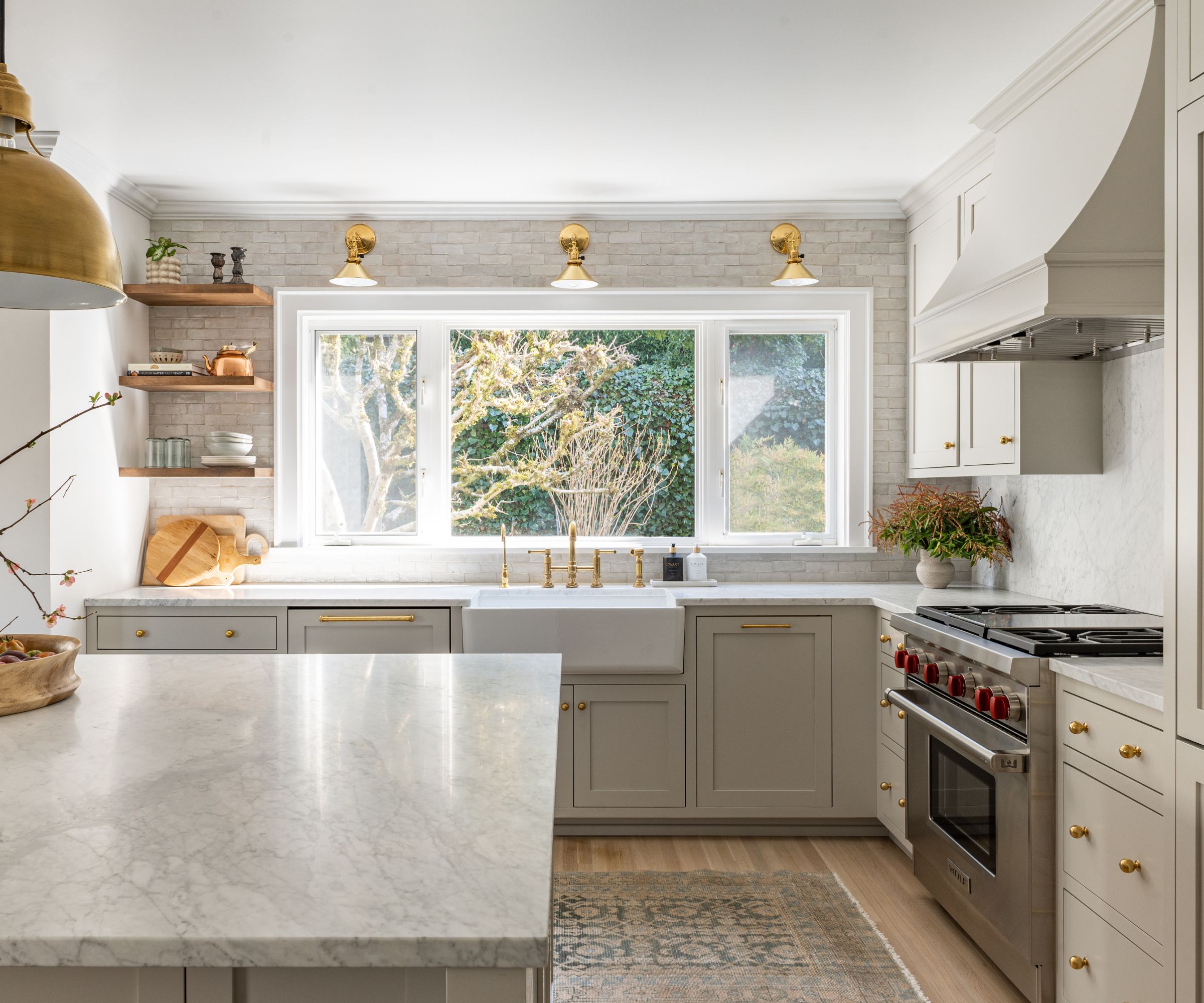 A gray kitchen with marble countertops and brass lighting