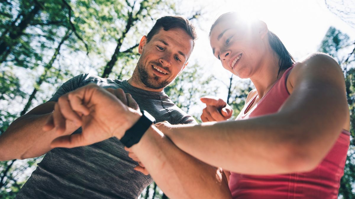 Man and woman checking smartwatches after a run