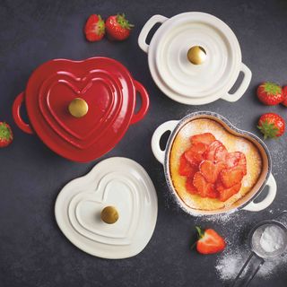 Red and cream Le Creuset-style heart shaped cookware from Aldi with a baked cake and strawberries