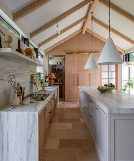 A wood and white kitchen with vaulted ceilings and marble countertops