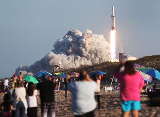 People watch as the SpaceX Falcon Heavy rocket lifts off from launch pad 39A at NASA’s Kennedy Space Center on April 11, 2019 in Titusville, Florida. The rocket is carrying a communications satellite built by Lockheed Martin into orbit.