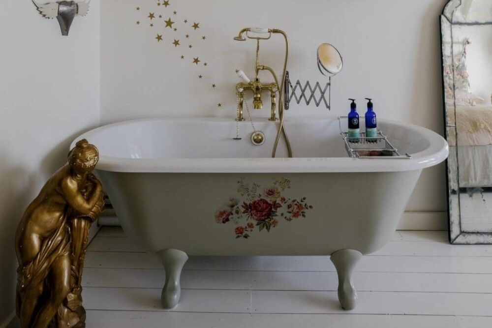 A Victorian styled bath with a bronze statue next to it
