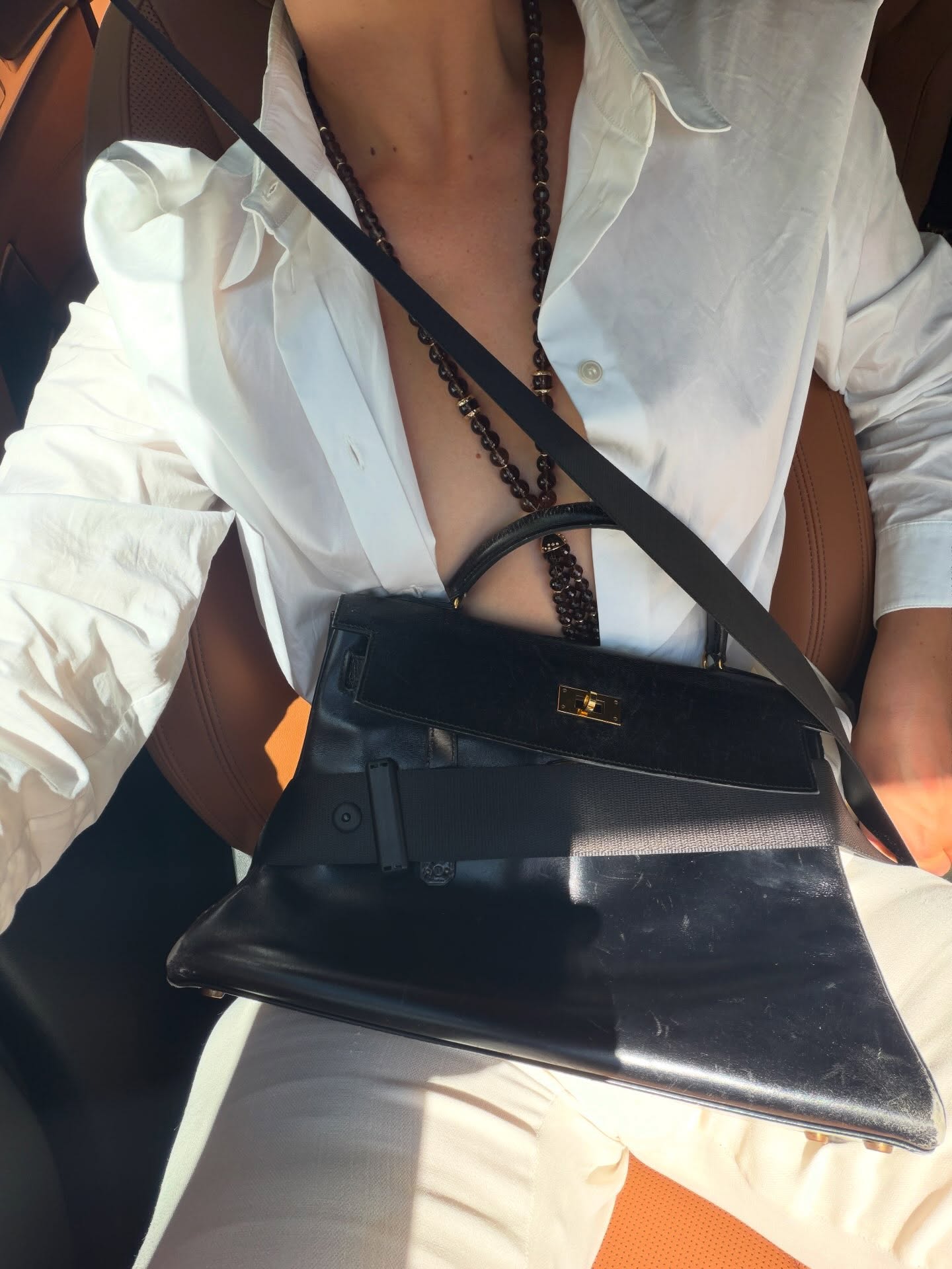 An image of @christietyler carrying an Hermes Kelly back with a pendant necklace, white jeans and white shirt.