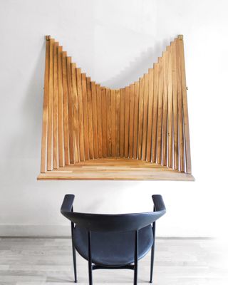 Wooden wall-mounted desk on a white wall wiht a navy blue desk chair in front