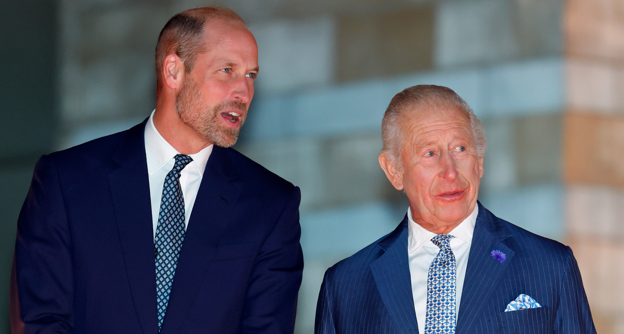 King Charles and Prince William talking to each other wearing blue suits