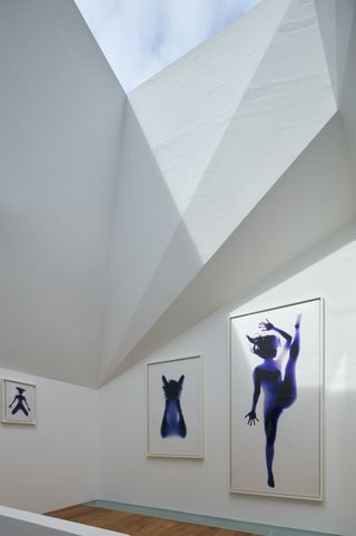Art displayed on white walls under skylight