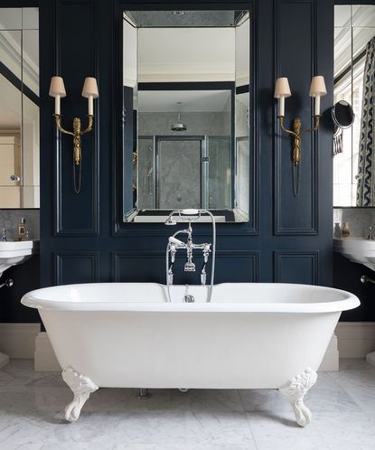 A photo from one of the best bathroom designers C.P. Hart showing a dark blue panelled bathroom with white bath and mirror.