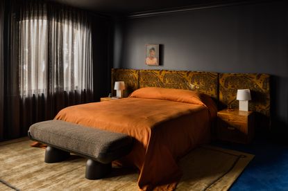 dark bedroom with large bed and orange bedding