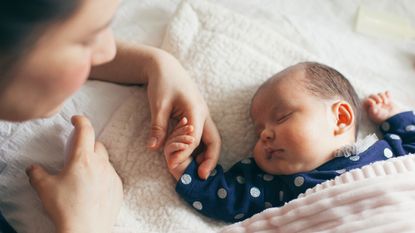 lullabies to help your baby to sleep - Mother holding baby girl hand - stock photo