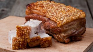 Pork belly with a crisp rind on a wooden board