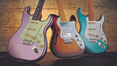 Two Squier Stratocasters and a Squier Thinline Telecaster on a black wooden floor leaning against a brick wall 