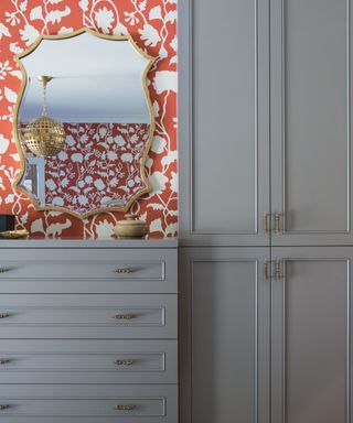 blue wardrobe and drawers with wall of orange wallpaper