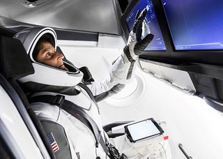 NASA astronaut Sunita Williams, wearing a SpaceX spacesuit, uses a display inside a mock-up of a SpaceX Crew Dragon spacecraft at the company's Hawthorne, California headquarters on April 3, 2018.