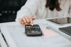 Young woman preparing home budget, using laptop and calculator