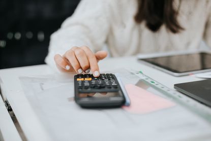 Young woman preparing home budget, using laptop and calculator