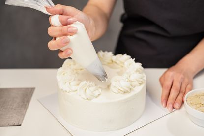 A woman decorates a cake.