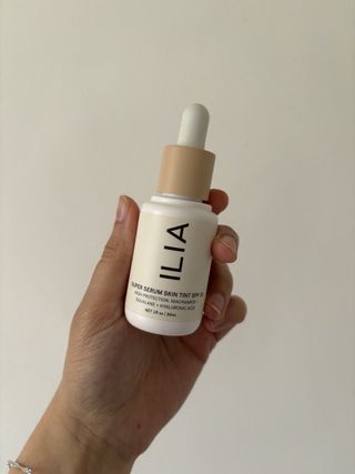 Mica holding a bottle of the Ilia Super Serum Skin Tint SPF 30